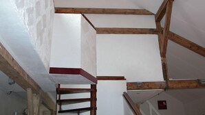 Ein Zimmer mit freiliegenden Holzbalken und weißen Wänden, das einen rustikalen oder Blockhaus-Stil widerspiegelt.