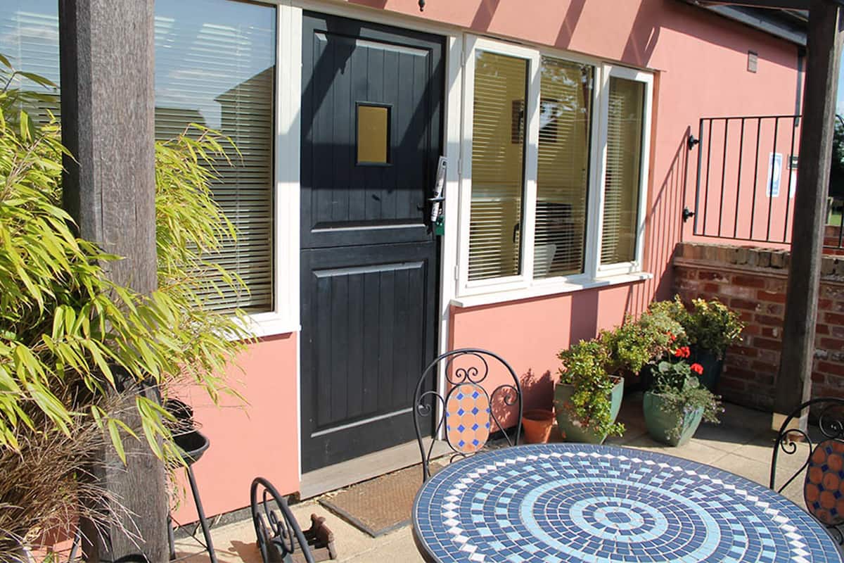 A patio with a tiled table, a black door, and potted plants.