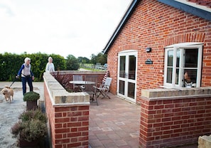 A brick house with a patio, a table, and chairs. - Damerons Farm Cottages (Ipswich)