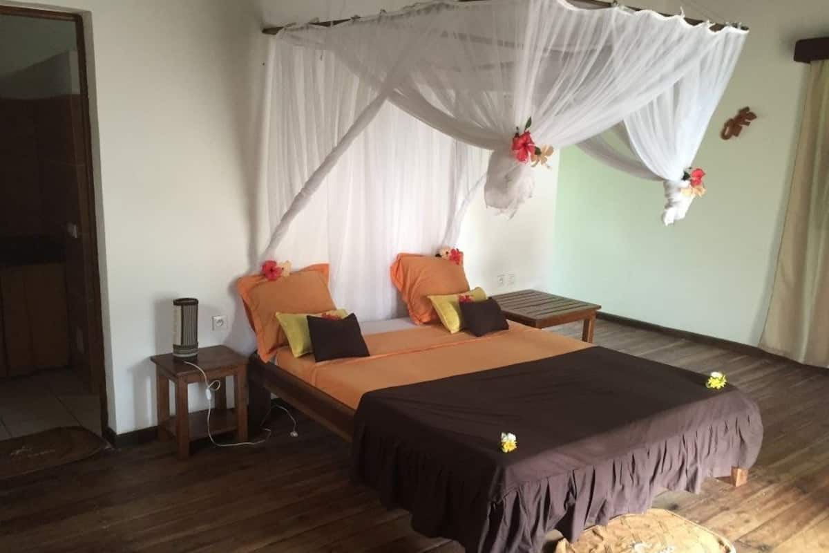 A bedroom with a bed, a bedside table, a lamp, and a curtain.