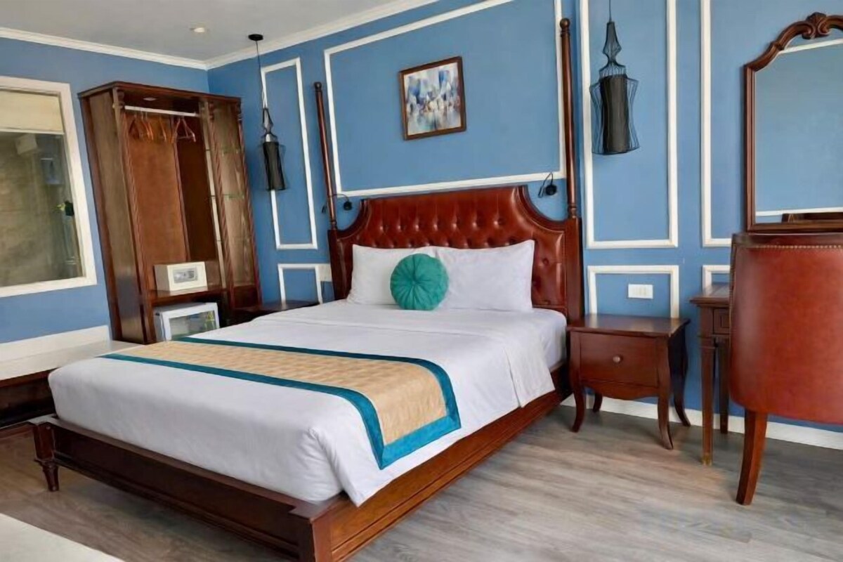 Une chambre d’hôtel avec un grand lit, une armoire en bois, une table de chevet et un miroir.