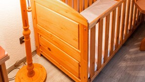 A wooden crib with a white mattress, a wooden nightstand, and a lamp. - Röhrs Gasthof (Sottrum)