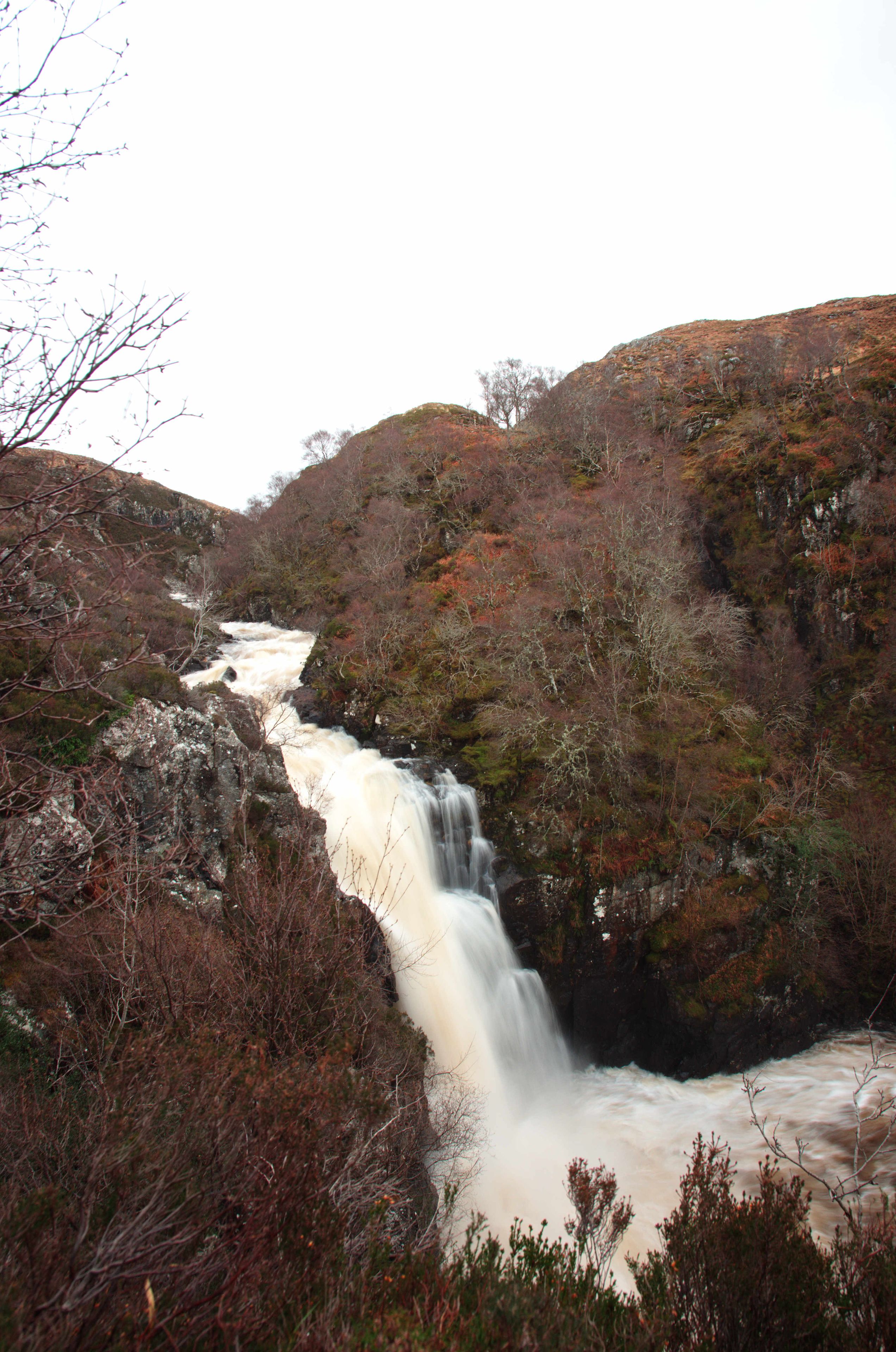 Une cascade entourée d’un paysage rocheux et d’une végétation clairsemée.