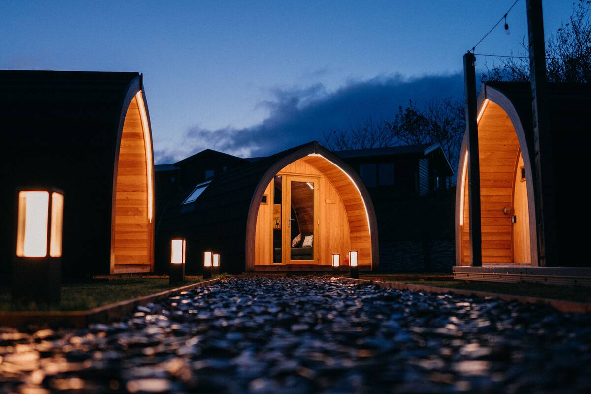 A building with three arched wooden doorways, each illuminated by a single light fixture.