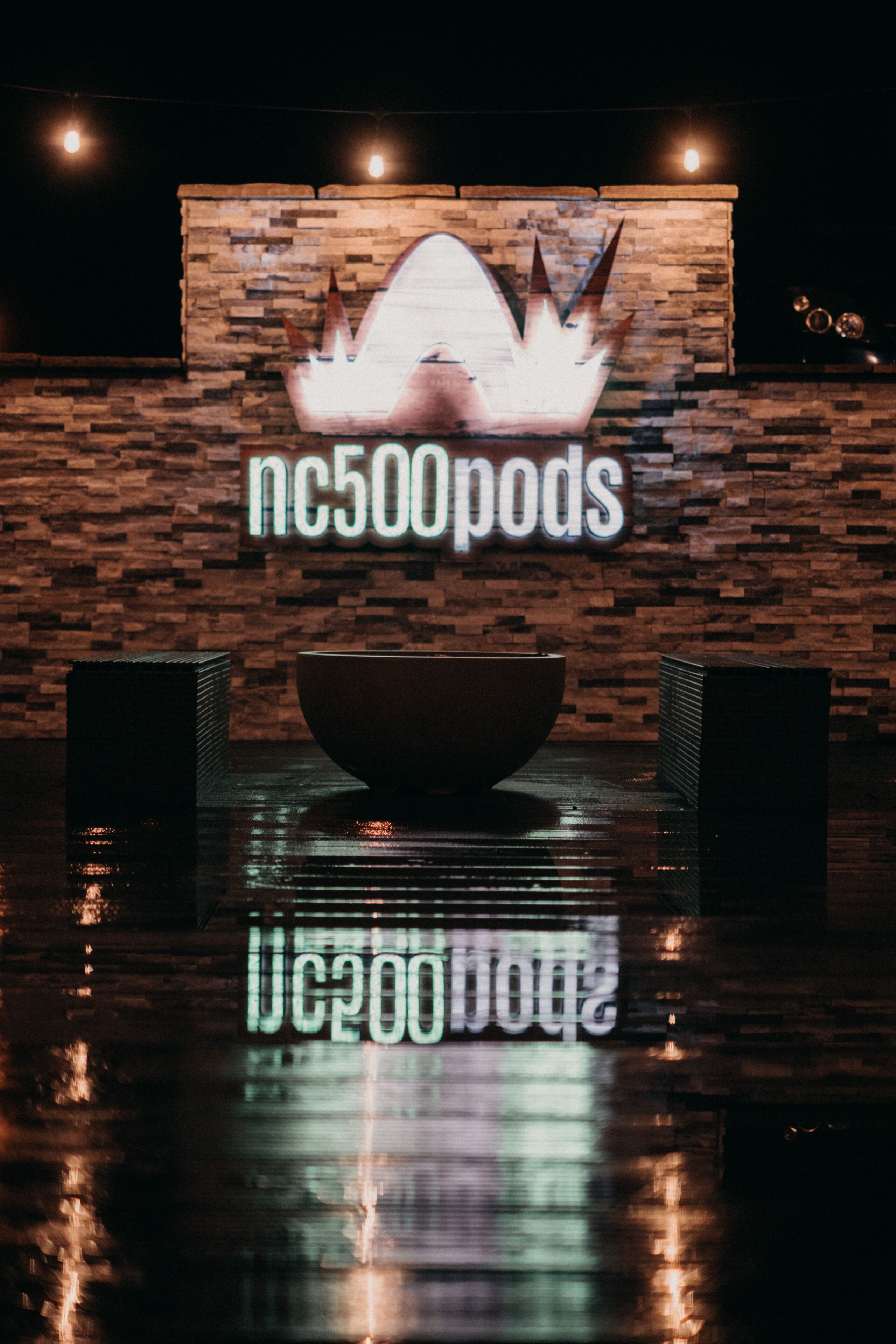 A sign with "nc500pods" and a large bowl in front of a brick wall.