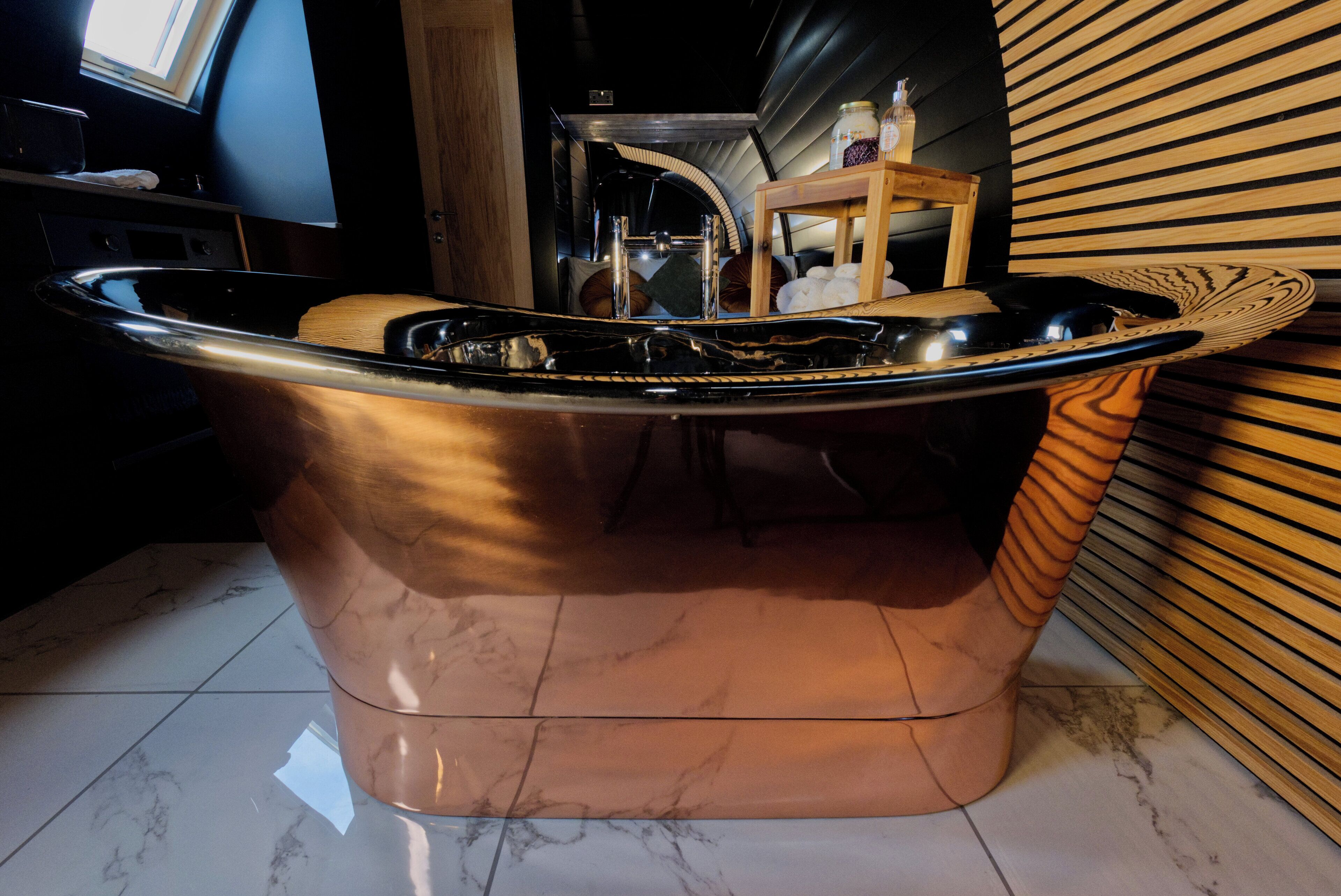 Un baño moderno con una bañera independiente, un tocador con espejo y un estante de madera con frascos.