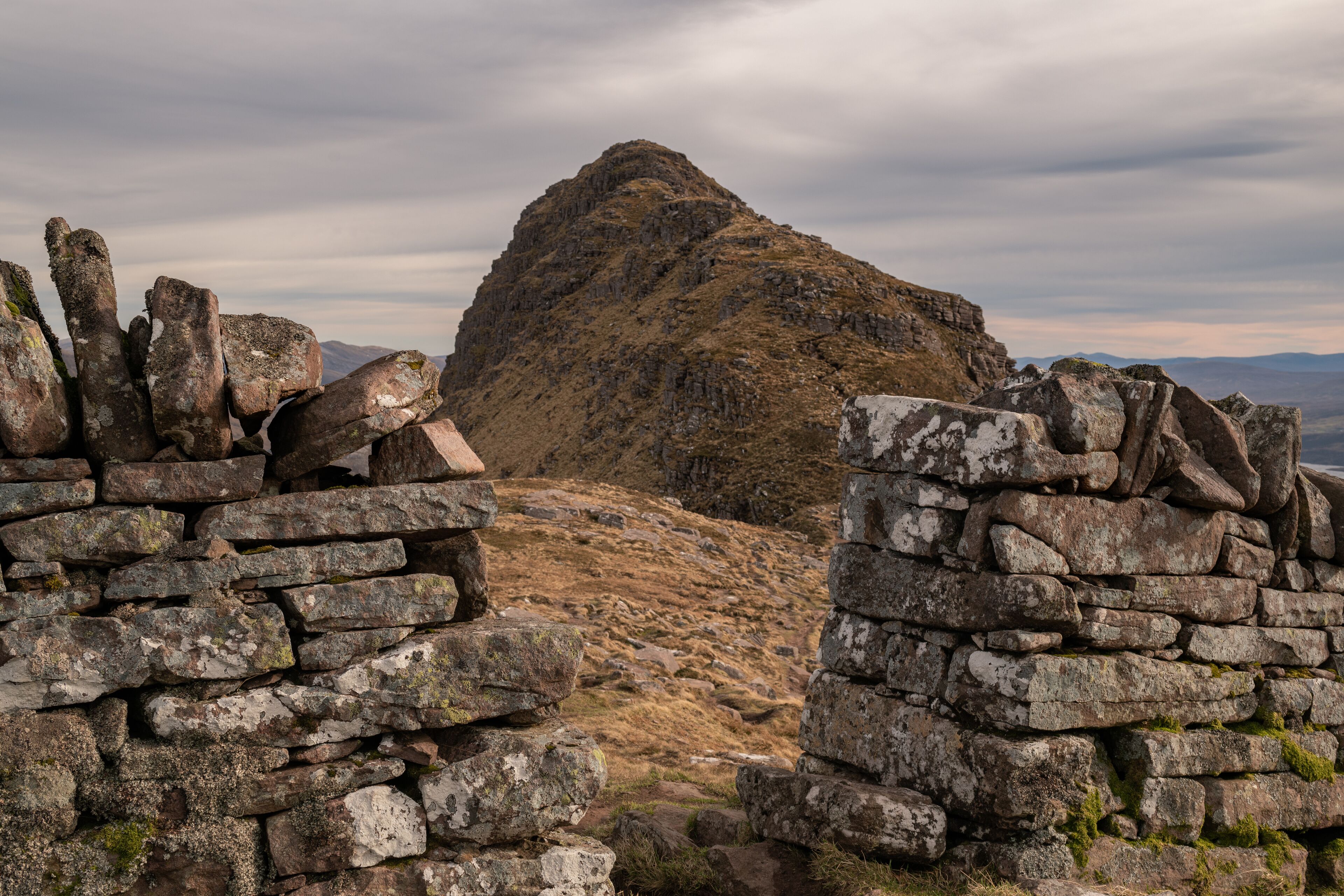 Un muro de piedra que conduce a un paisaje montañoso.