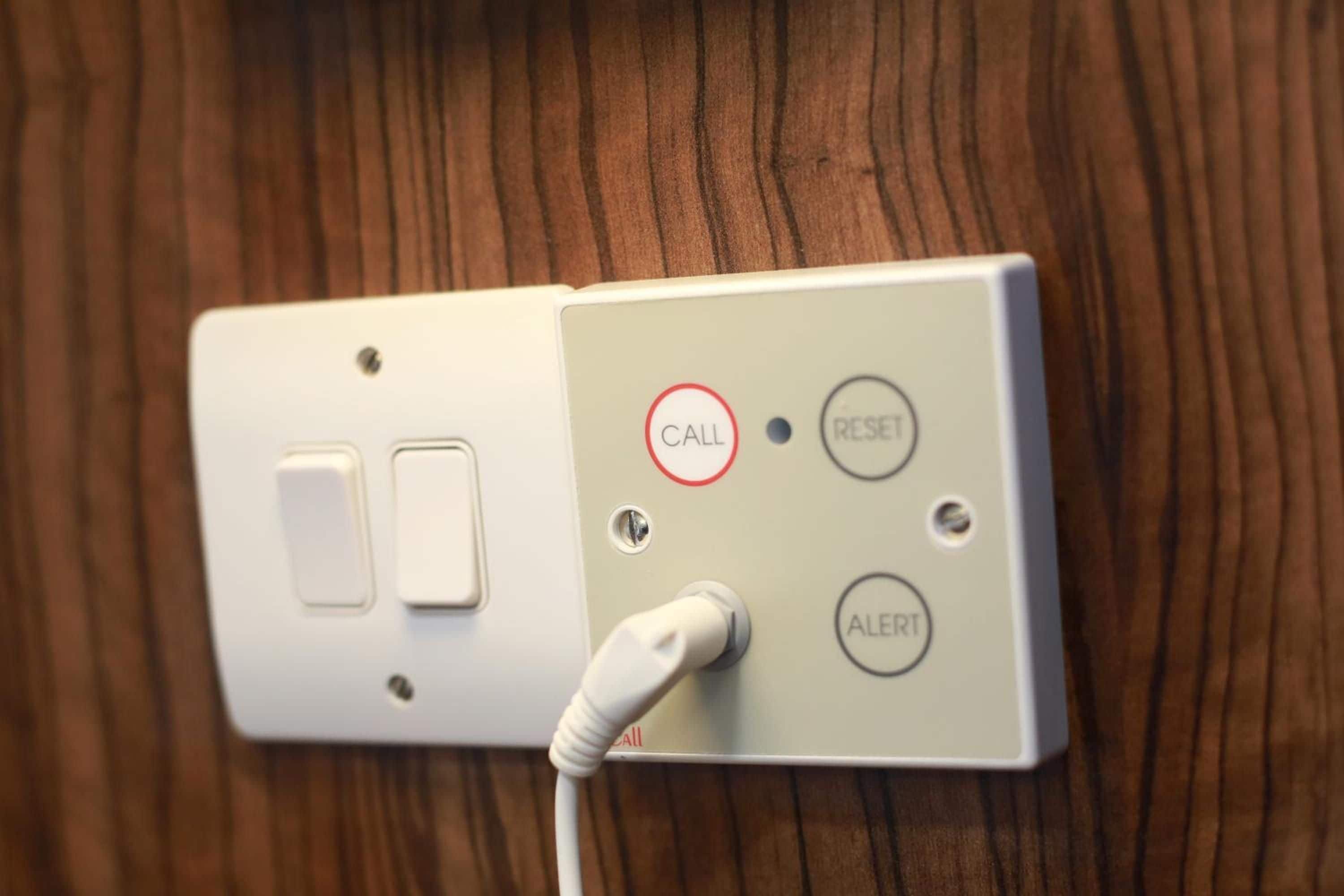A wall-mounted electrical outlet with a white plug connected to a white cord.