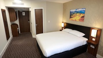Habitación de hotel con una cama grande, un cuadro en la pared y suelo alfombrado.