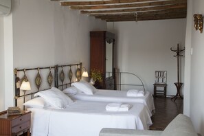 Habitación de hotel con dos camas, un armario de madera, una silla y una lámpara de pie.