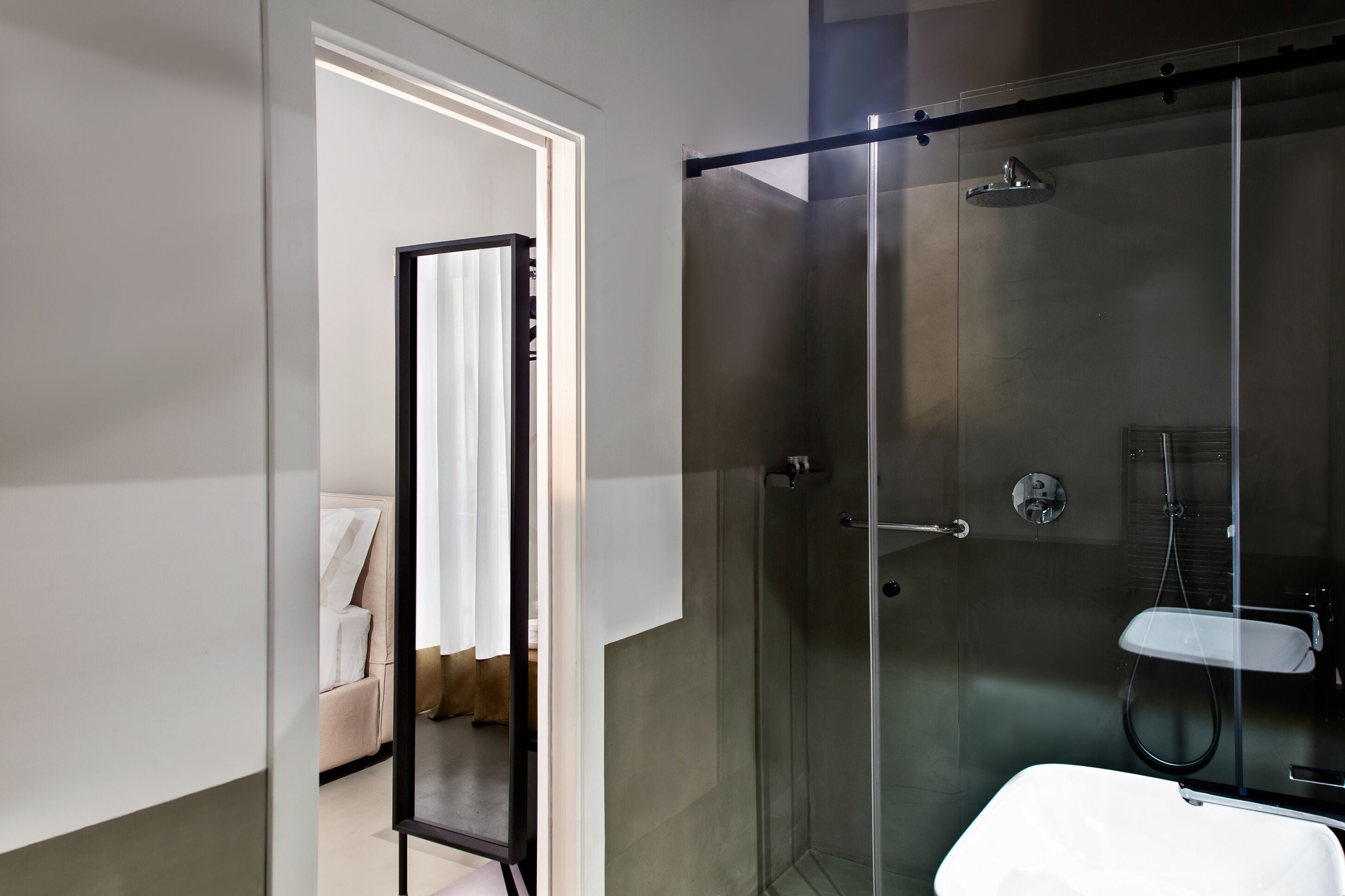 Une salle de bain moderne avec une douche à parois de verre, un lavabo blanc et un porte-serviettes apparent.