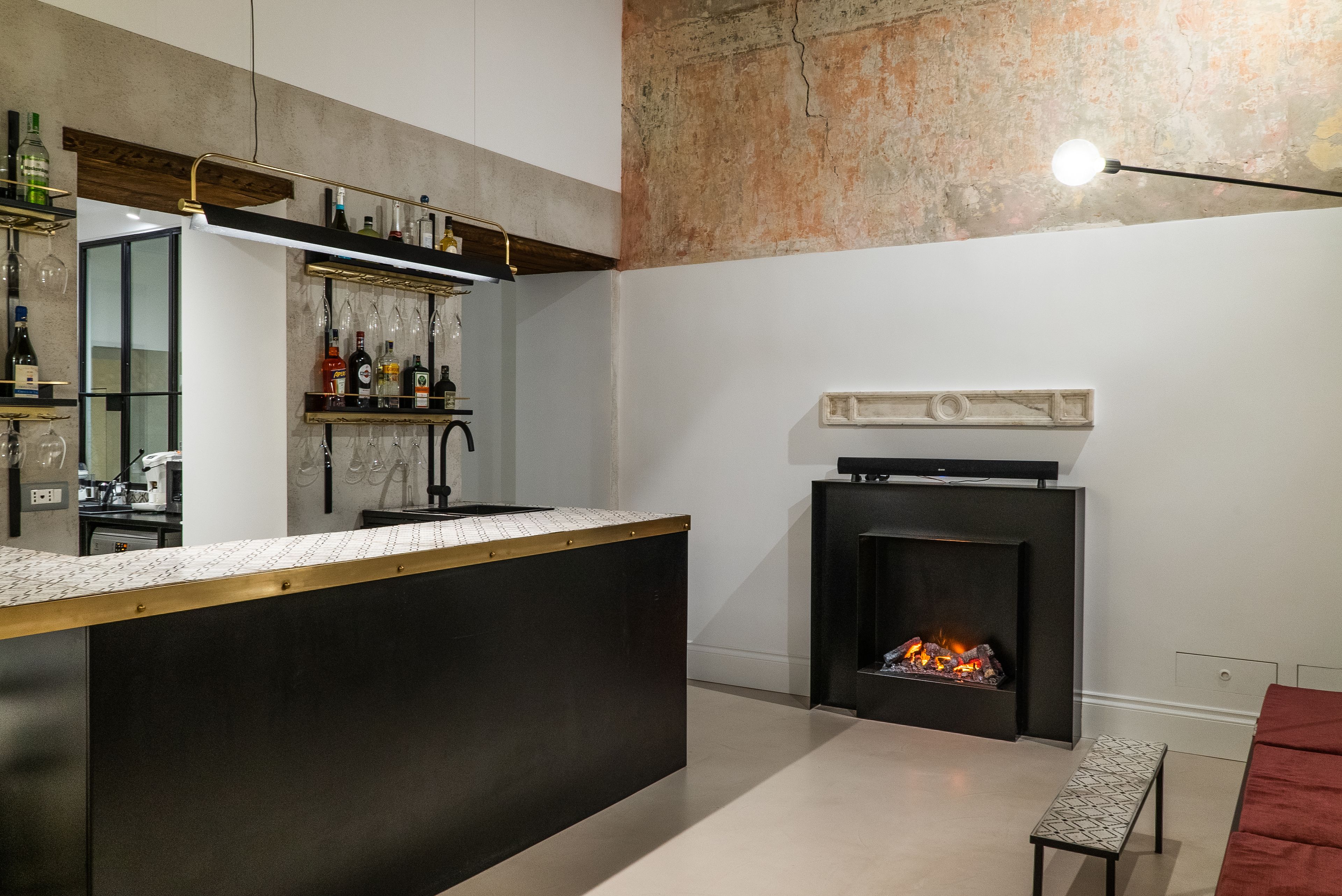 A modern kitchen with a bar area, a fireplace, and a bench.