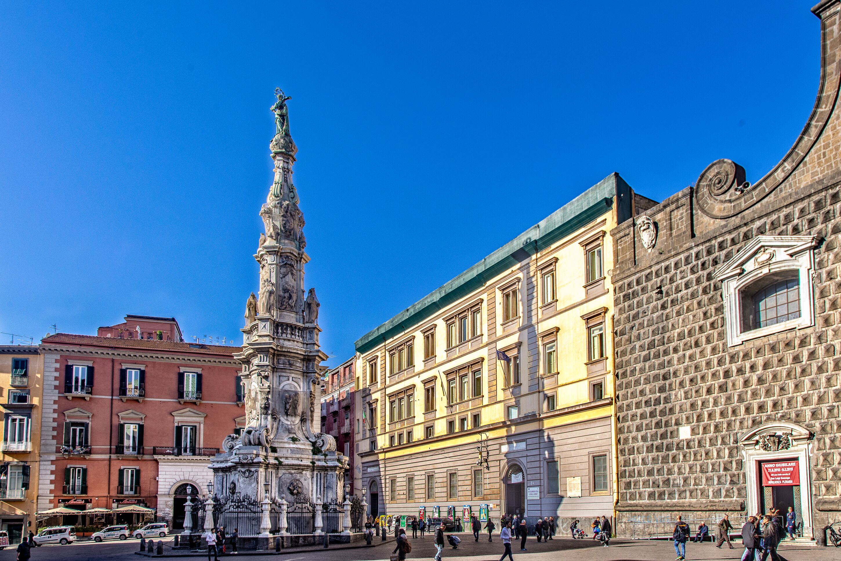 Una piazza storica con una fontana imponente, architettura classica e un cielo azzurro.