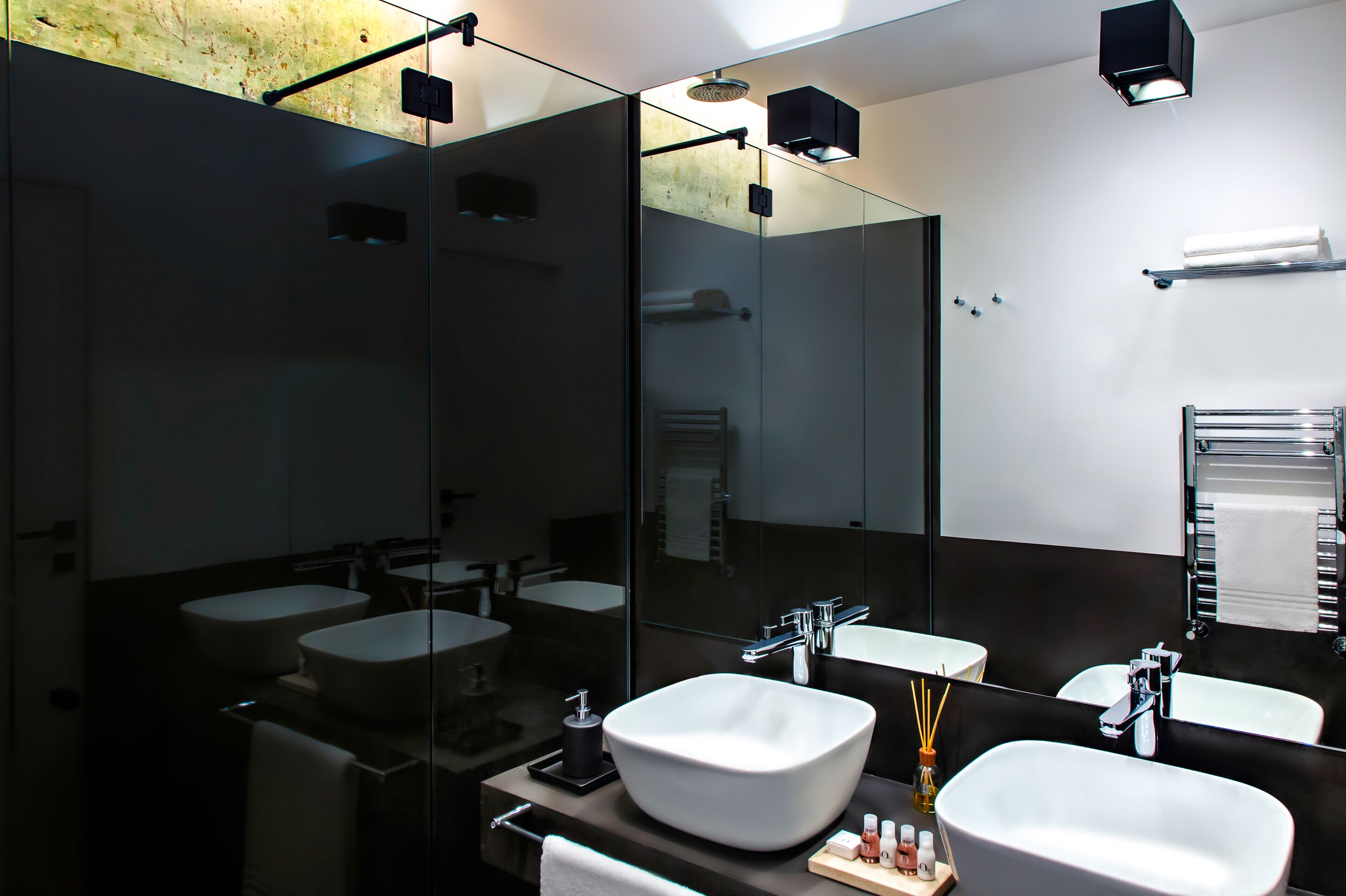 A modern bathroom with two sinks, a large mirror, and a glass-enclosed shower area.