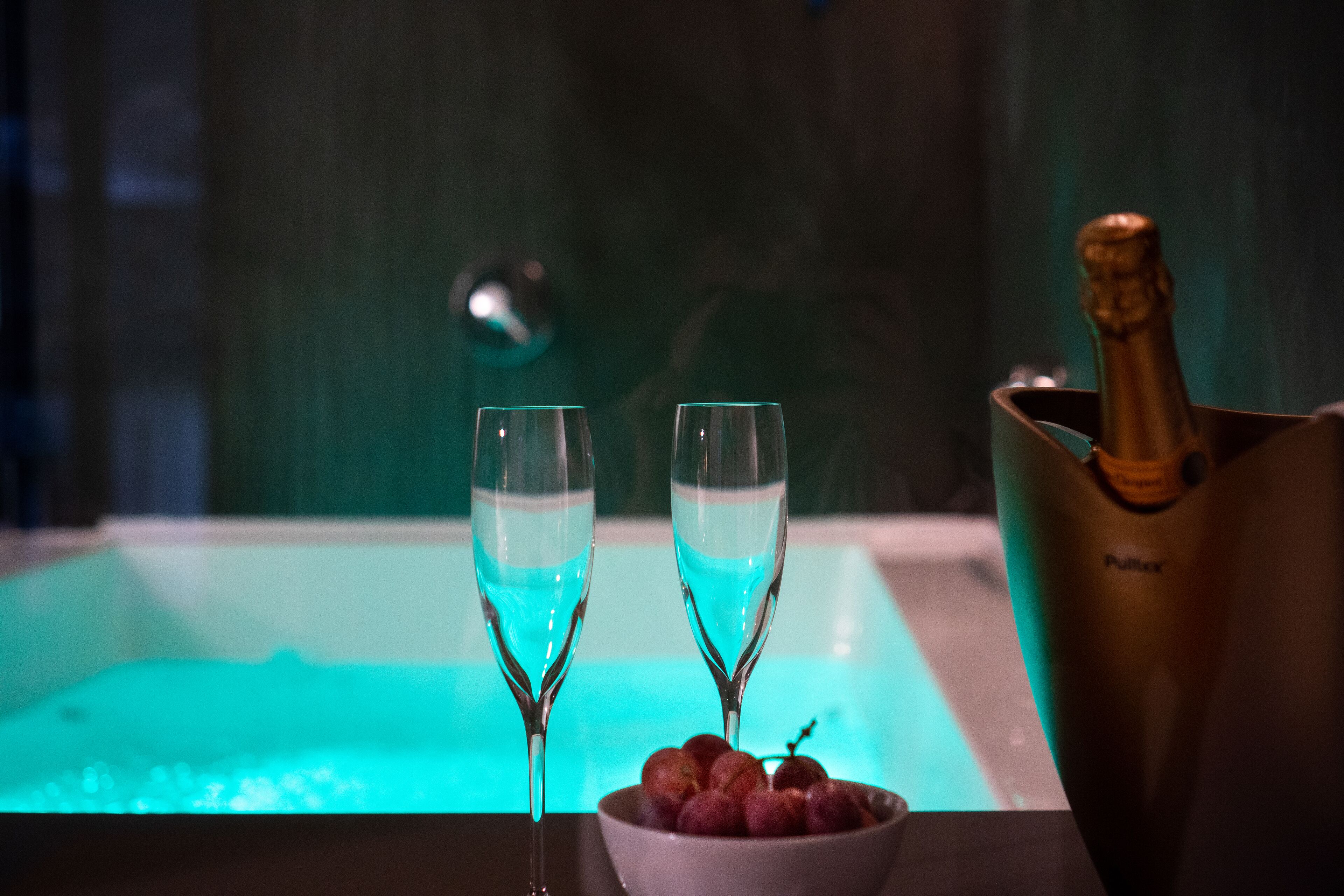 Due bicchieri da champagne su un tavolo, con un secchiello dorato pieno di champagne e una ciotola di ciliegie.