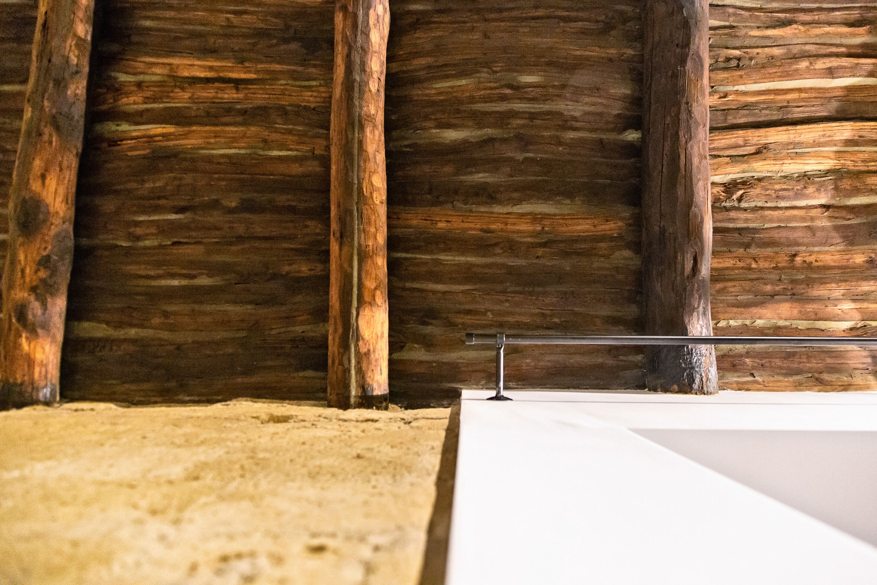 Una stanza con travi in legno, un letto bianco e un tappeto beige.