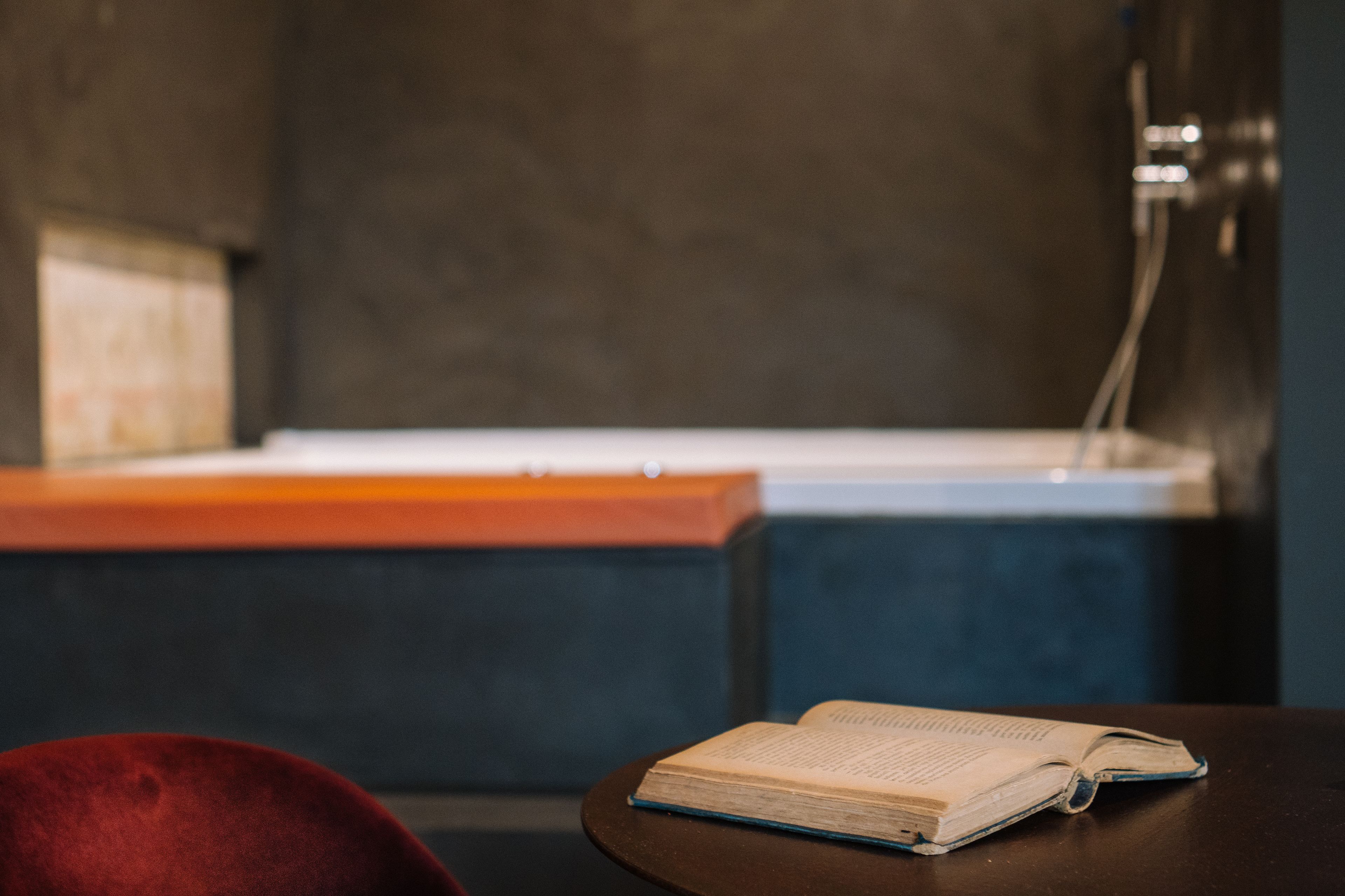 Une pièce avec une table en bois, une chaise rouge et un livre ouvert.