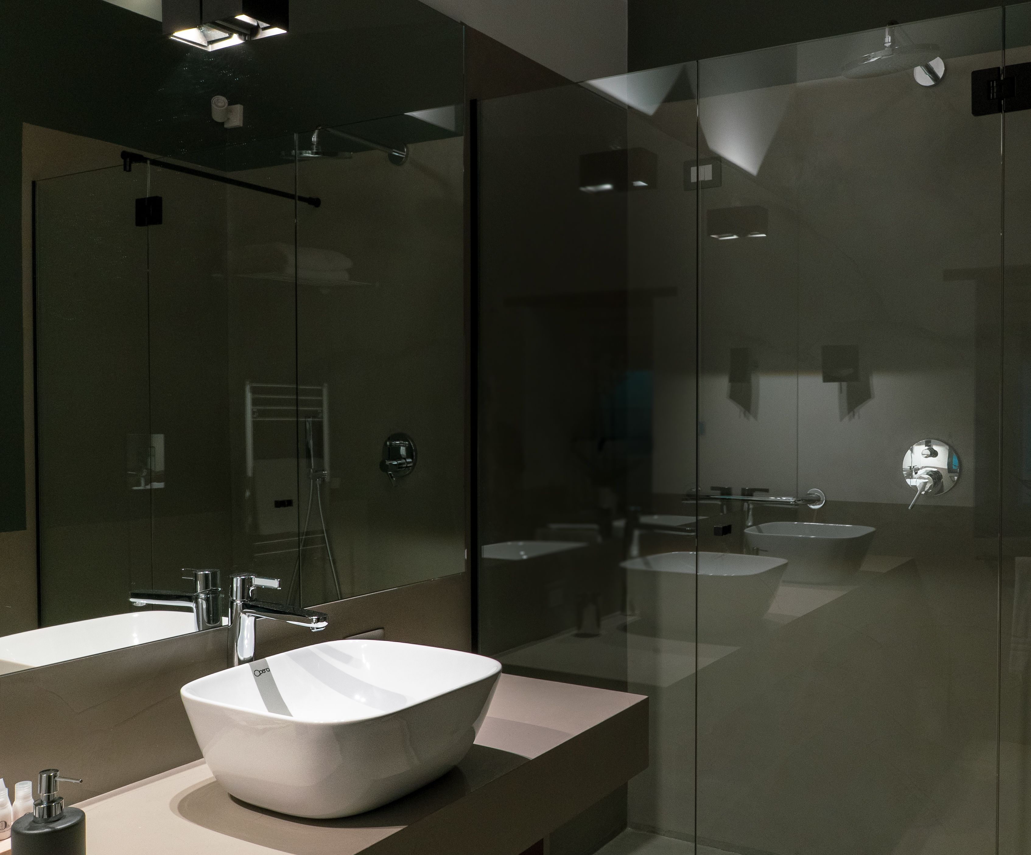 A modern bathroom with a large mirror, two sinks, and a glass shower enclosure.