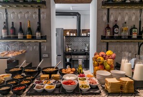 A breakfast buffet with various food items, wine bottles, and glasses on shelves.