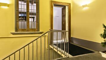 A staircase with a metal railing, a wooden door, and a black mat at the bottom.