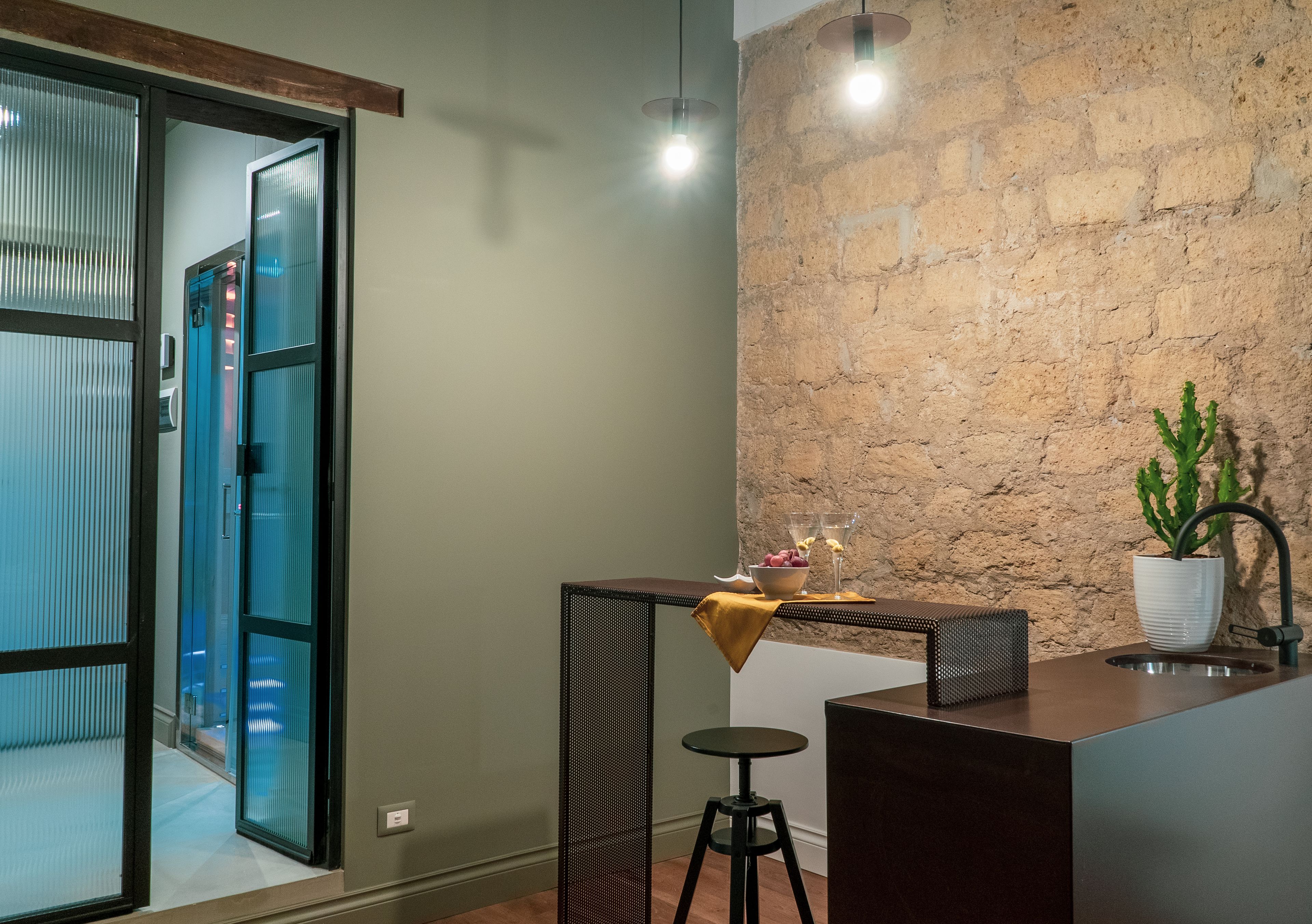 A modern kitchen with a stone wall, a bar area, and a potted plant.