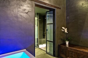 A modern bathroom with a glass shower enclosure, a wooden vanity, and a potted orchid.