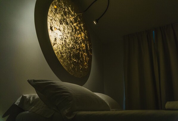 Ein schwach beleuchteter Raum mit einer runden Wandgestaltung und einem Bett mit Kissen.