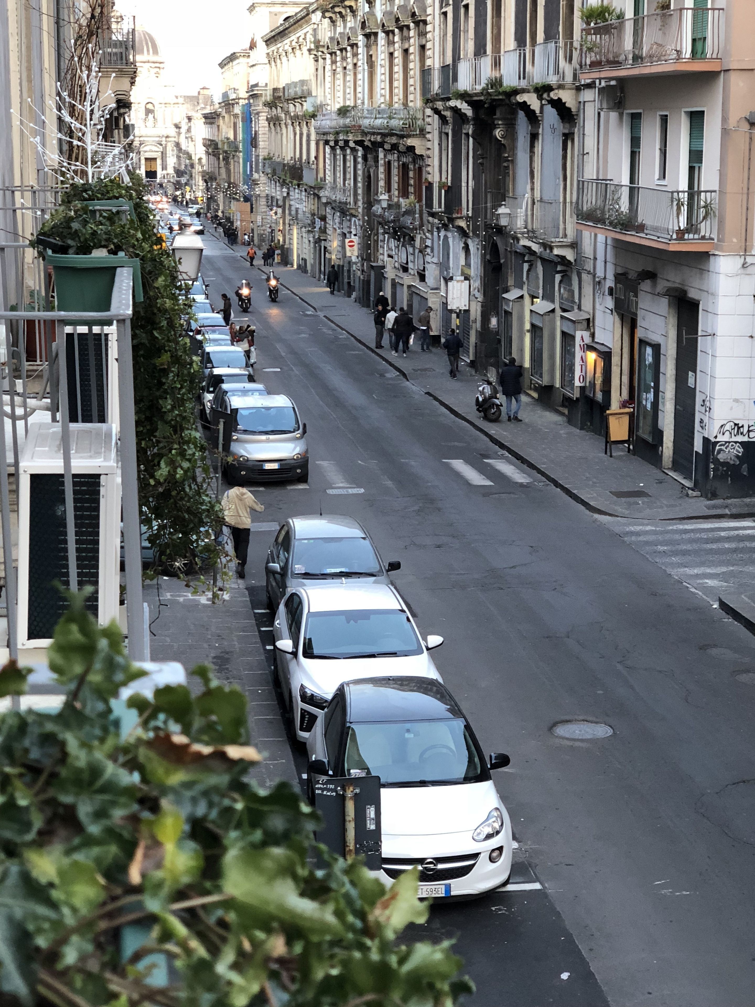 A street lined with parked cars and buildings.