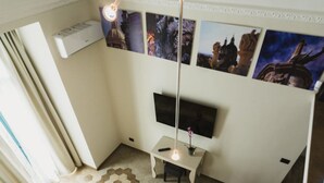A room with a flat-screen TV mounted on the wall, a small table with a lamp, a decorative wall hanging, and a hexagonal patterned floor. - Catania House (Catania)
