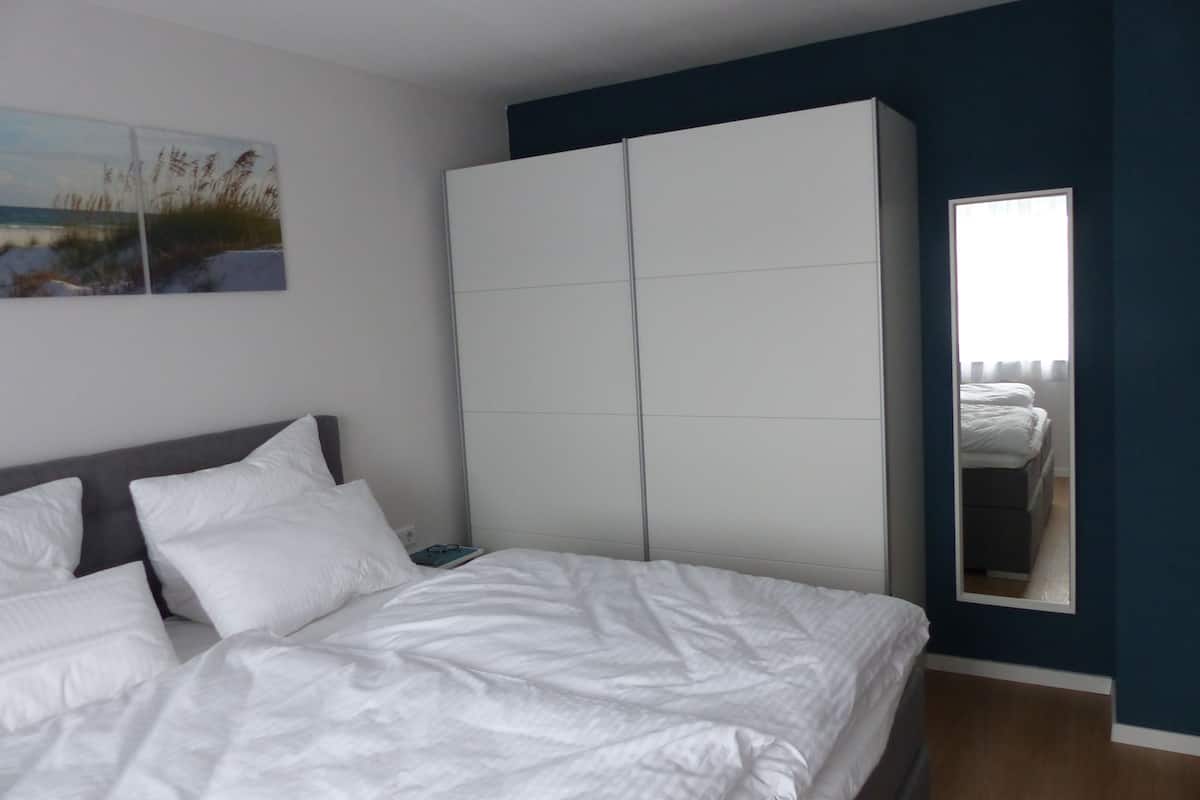 Une chambre à coucher avec un lit, une armoire, un miroir et un tableau accroché au mur.