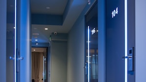 A modern hallway with glass doors numbered 104 and 105, leading to rooms. - Athens Platinum Rooms and Suites (Athens)