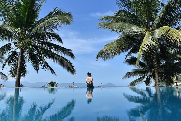 Una piscina al aire libre, sombrillas, sillones reclinables de piscina