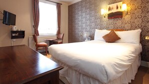A hotel room with a large bed, a wooden desk, a chair, a television, and a window with curtains. - White Hart, Andover by Marston's Inns (Andover)