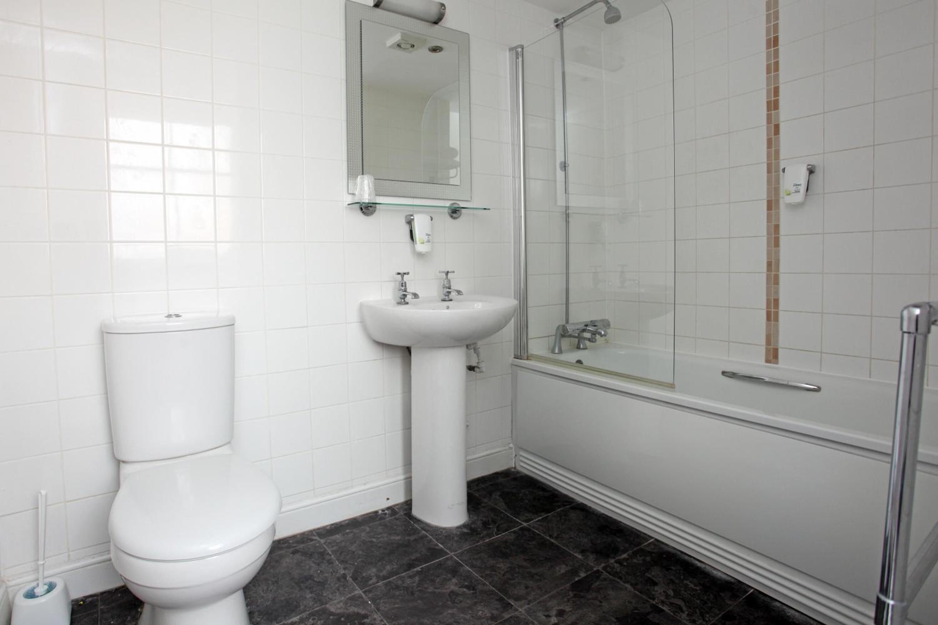 A bathroom with a toilet, sink, and glass-enclosed shower.
