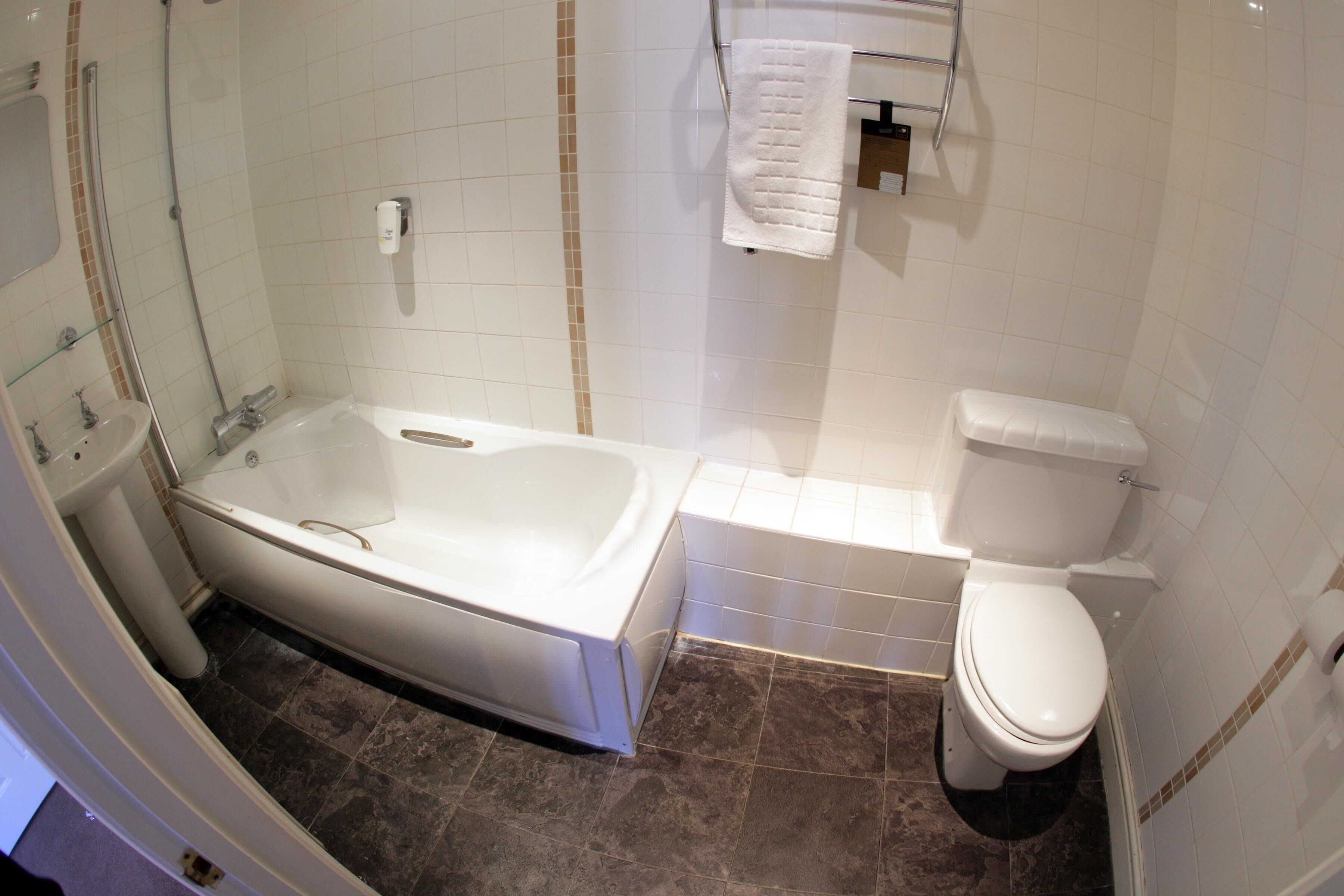 Een badkamer met een bad, toilet en douche.