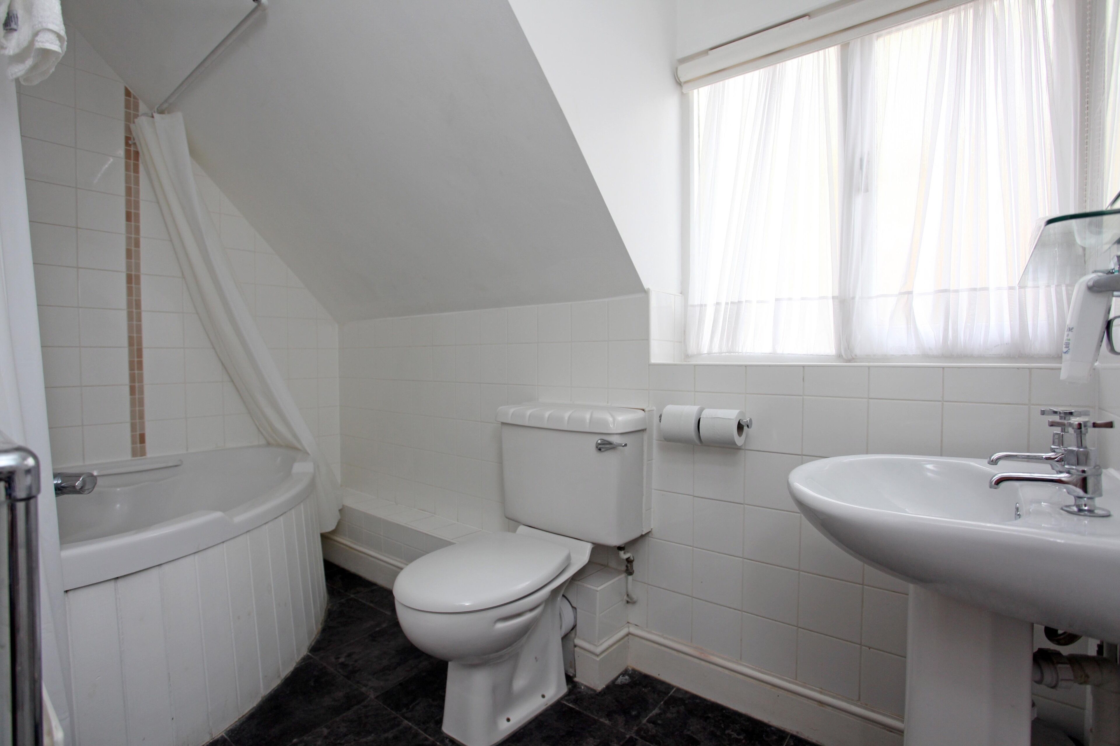 Et badeværelse med badekar, toilet og håndvask.