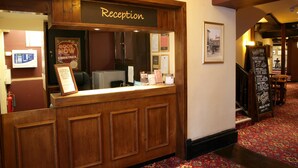 A reception desk with a sign reading "Reception" and a "Book Now for Christmas" poster. - White Hart, Andover by Marston's Inns (Andover)