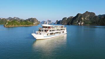 Experience the serene beauty of a river cruise amidst lush green hills and rugged cliffs.