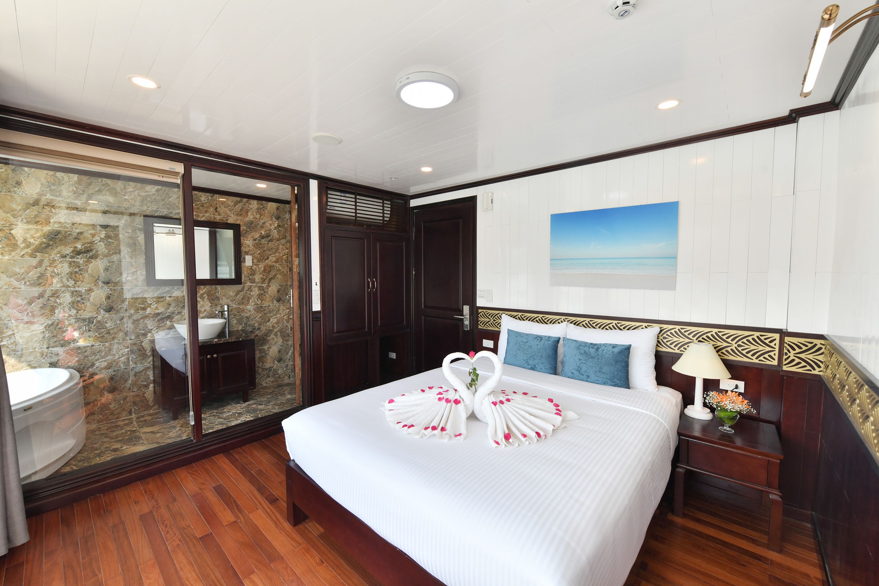 A hotel room with a large bed, a bathroom with a stone wall, and a view of the sea.