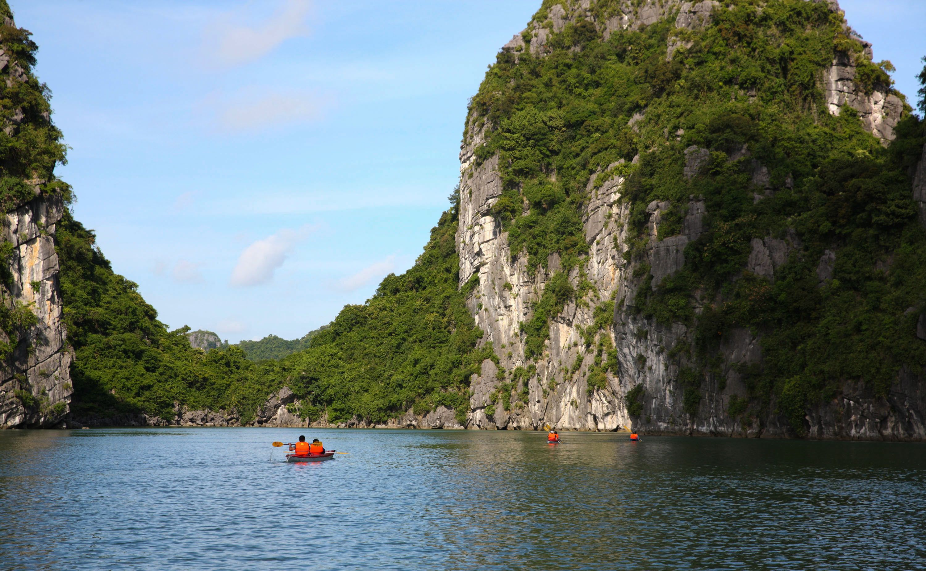 A river with a boat and a rocky cliff.