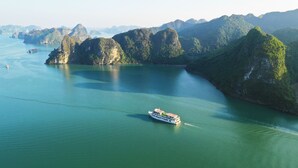 A river cruise ship navigating through a series of limestone islands. - Halong Sapphire Cruise (Tuan Chau)