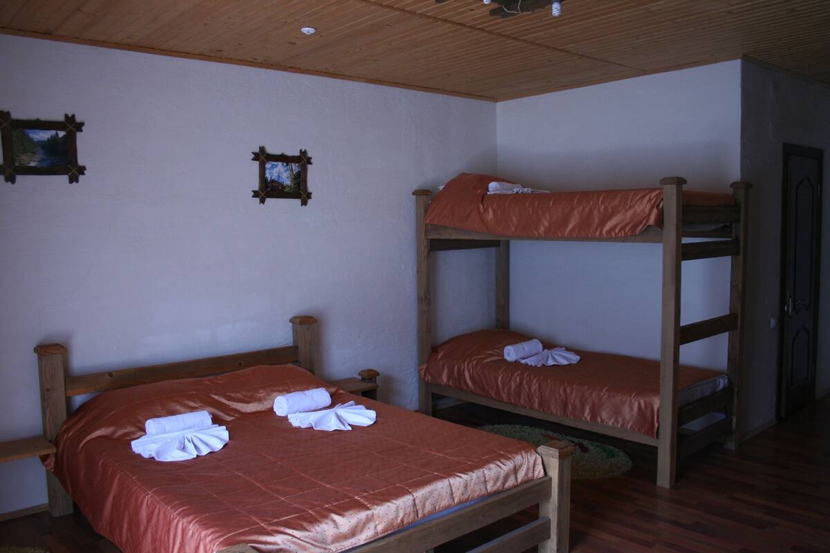 A room with two bunk beds, wooden headboards, and a wooden ceiling.