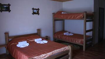 A room with two bunk beds, wooden headboards, and a wooden ceiling.