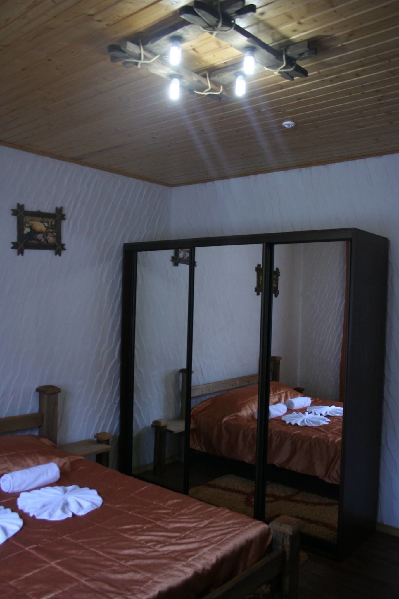 Une chambre avec deux lits, des poutres apparentes en bois au plafond et un grand meuble avec une porte-miroir.