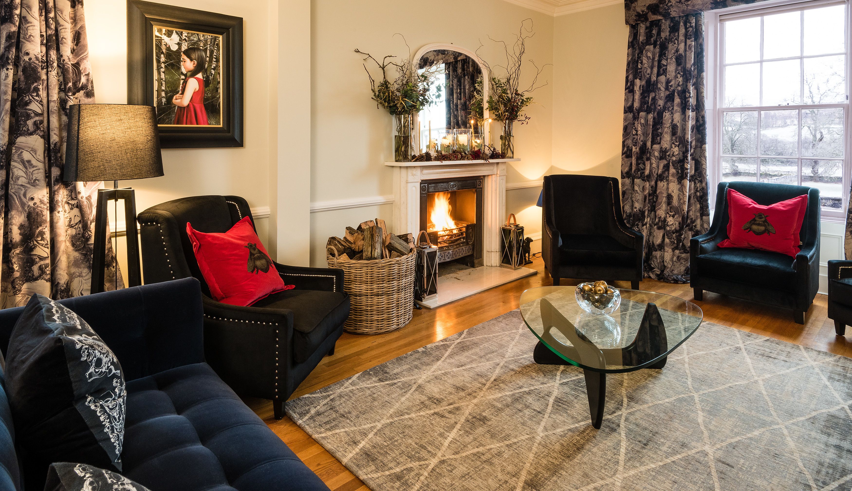 A cozy living room with a fireplace, two armchairs, a sofa, and a coffee table.