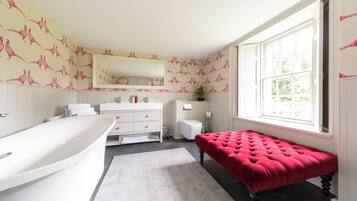 Bathroom features a bathtub, vanity with mirror, and tufted bench.