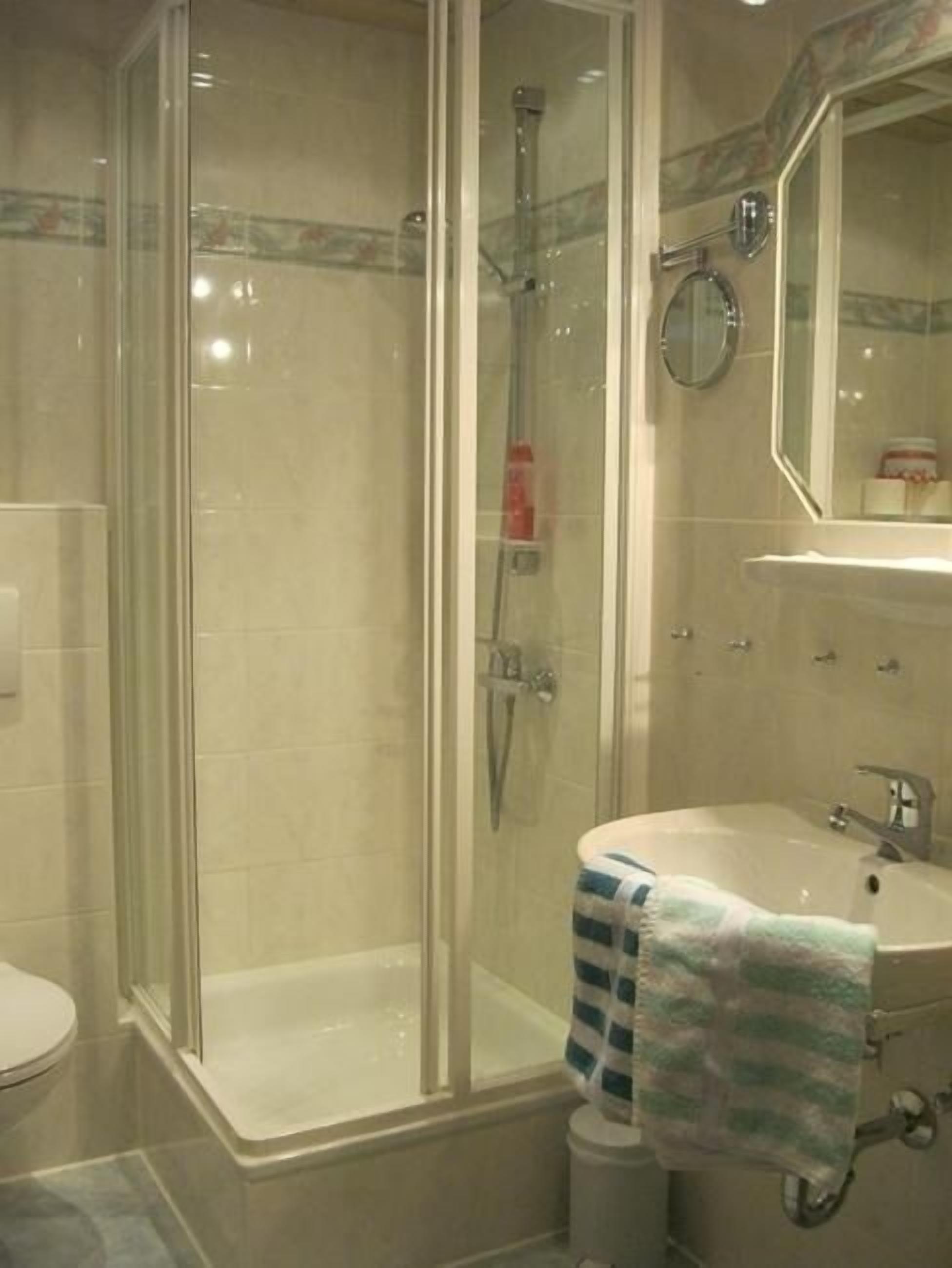 Une salle de bain avec une douche à parois de verre, un lavabo avec une serviette et un miroir.