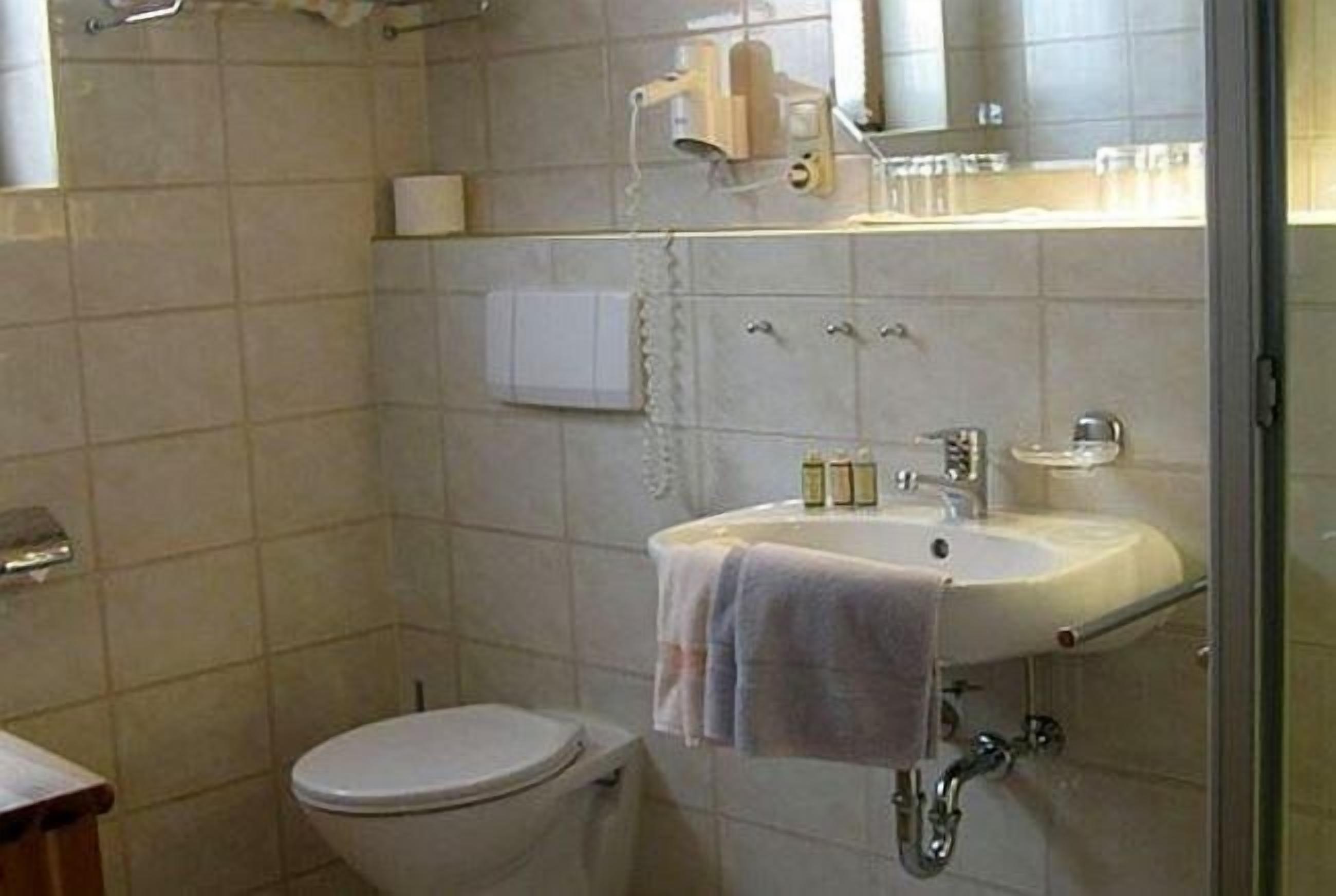 A bathroom with a toilet, sink, and mirror.
