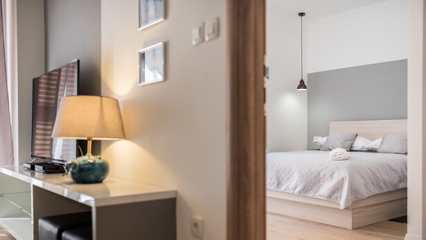 Une chambre d’hôtel moderne équipée d’un lit, d’un bureau avec une lampe et d’un téléviseur.