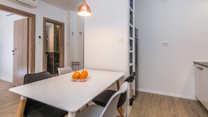 Une cuisine moderne avec des meubles blancs, un plan de travail blanc et un luminaire suspendu.